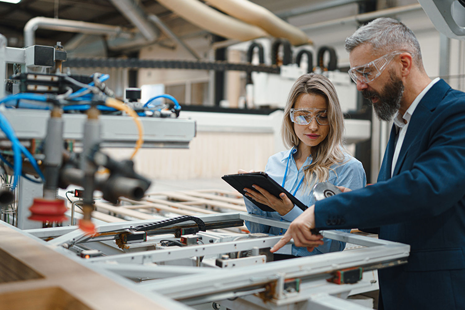 Two engineers inspecting machines in an automated wood processing facility